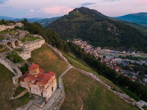Aerial view of Berat Castle featuring the Holy Trinity Church, ancient stone fortifications, and the surrounding hills at dusk in Berat, Qarku i Beratit, Albania.
