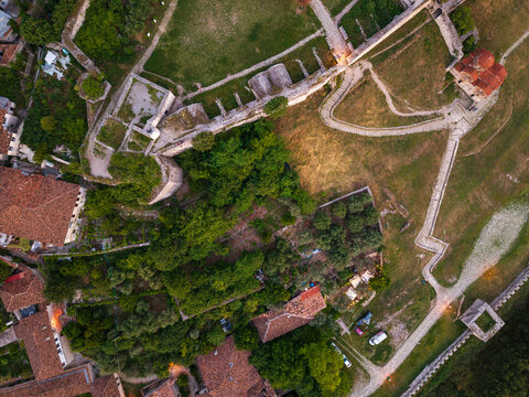 Aerial view of the ancient stone walls and green courtyards of Berat Castle with the Holy Trinity Church and historic rooftops in Berat, Qarku i Beratit, Albania.