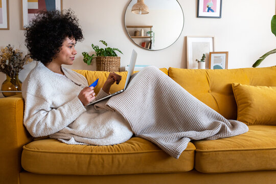 Woman shopping online with credit card on sofa