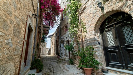 Obraz premium Chios, Greece - May 24, 2026: Scenic street view of Mesta village on Chios Island, Greece, featuring stone-built houses, narrow cobblestone streets, old walls, and the historic atmosphere