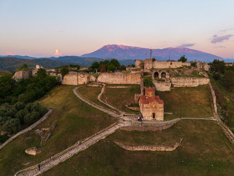 Aerial view of Berat Castle featuring the Holy Trinity Church and ancient stone walls with Mount Tomorr in the background at sunset Berat, Qarku i Beratit, Albania.