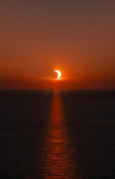 Partial solar eclipse at sunset over the ocean with the sun's reflection on the water of the Mediterranean near Menorca