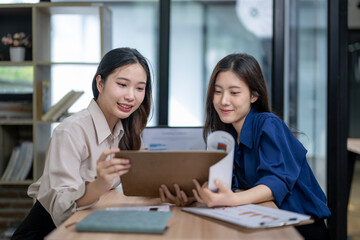 Obraz premium Asian businesswomen collaborating on paperwork and planning strategy in office