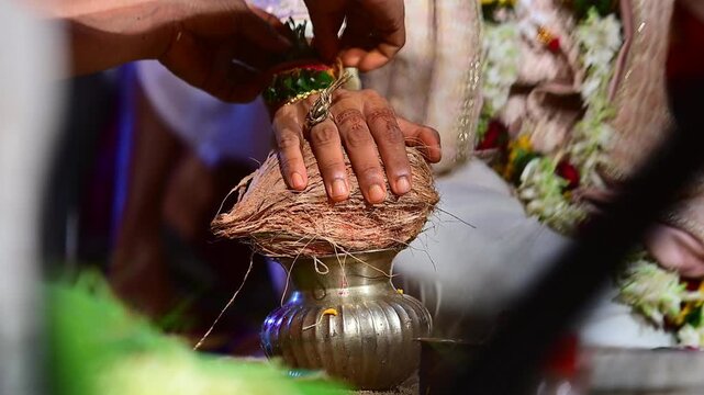 Close-up footage of bride and groom hands participating in traditional Hindu wedding rituals during a marriage ceremony in India. The scene captures sacred customs, ceremonial offerings