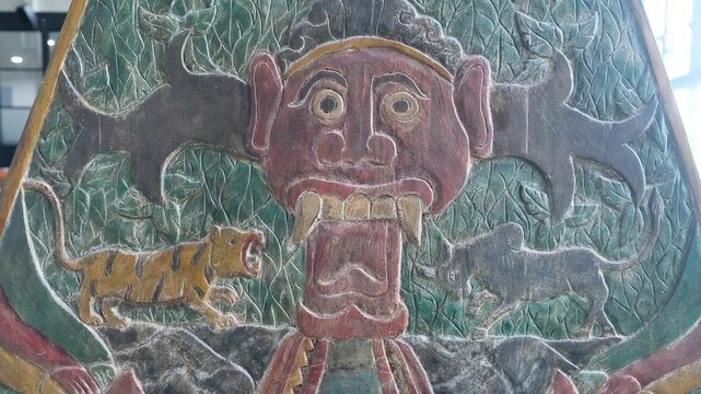 Traditional carved puppet artwork featuring a stylized character with decorative cultural motifs and aged texture.