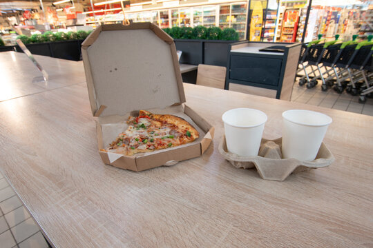 Pizza and drinks on a table in a grocery store food area during the day