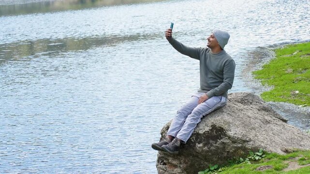 Man sitting on rock checking phone during Kareri lake trek, Dhauladhar range of Himachal Pradesh India
