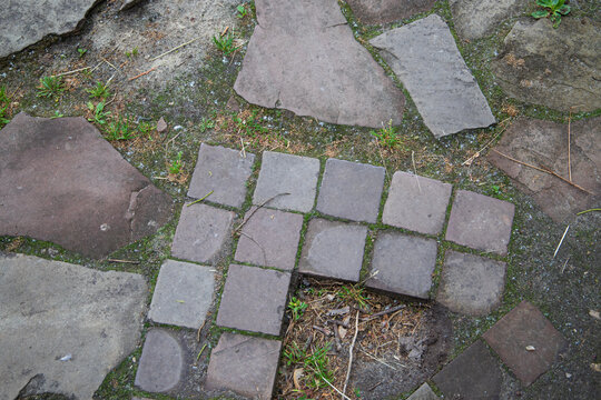 Texture of old stone pavement walkway with green moss close up, flagstone garden path background with granite cobblestone border curb, rustic landscape design full frame top view mockup.