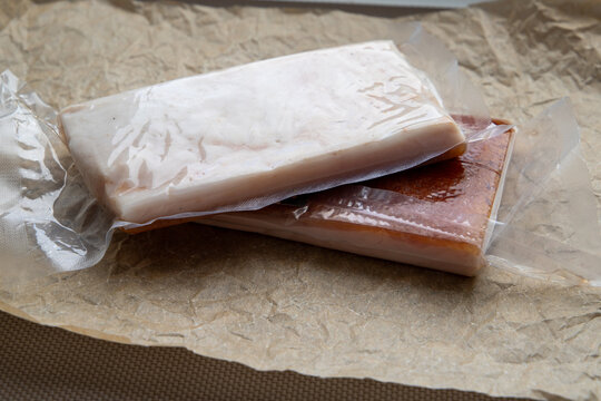 Two pieces of vacuum packed pork lard on crumpled craft paper.