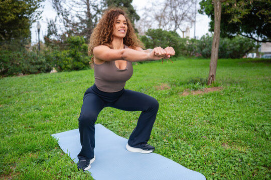 Woman doing outdoor fitness squat exercise in park