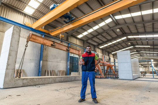 Worker in concrete structures factory in wide angle image with work uniform.