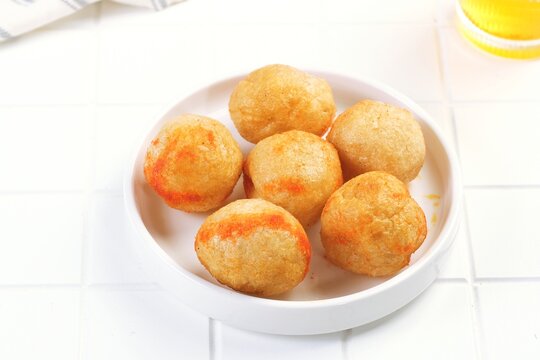 Crispy Indonesian fried tofu balls or tahu bulat served on white plate with simple food styling and clean bright background.