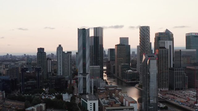 Aerial view of London Canary Wharf skyscrapers during sunset over Millwall Dock financial district.