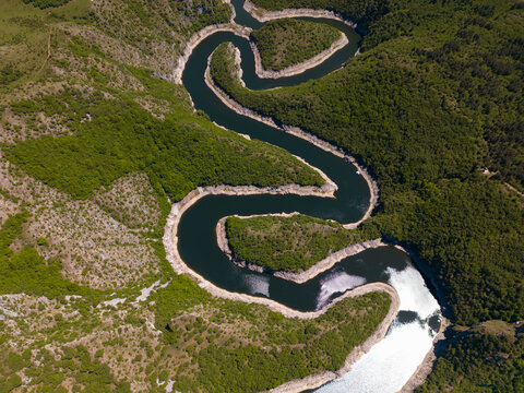 High angle aerial view of the famous Uvac River meanders canyon in Serbia. Stunning drone landscape of curvy river flowing through deep rocky cliffs and green hills.