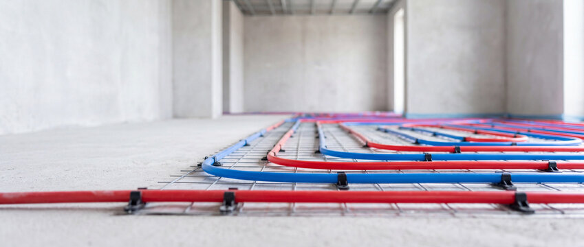 Underfloor heating installation with red and blue pex pipes laid in concrete floor for radiant heat
