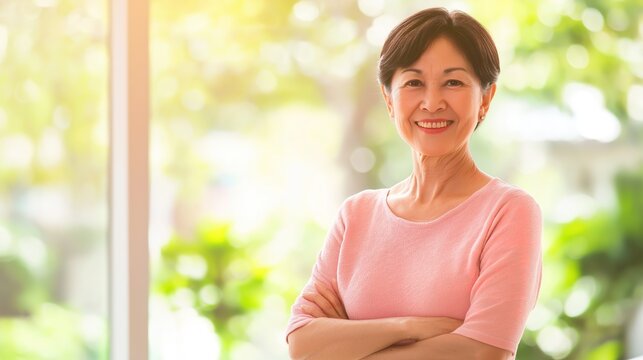 Lifestyle portrait of vibrant beautiful Japanese woman in her 50s, confident smiling pose with crossed hands, elegant casual outfit, bright airy white room, natural and studio soft lighting, clean col
