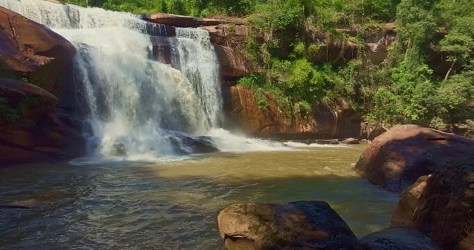 Beautiful rainy season aerial shot of Tat Huang Waterfall in Loei Province. Positioned between Thailand and Laos, this international waterfall is framed by tropical forest, peaceful mountains