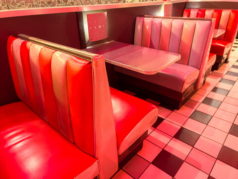 Dining area with red and purple booths in a modern restaurant during evening hours with low lighting and checkered floor