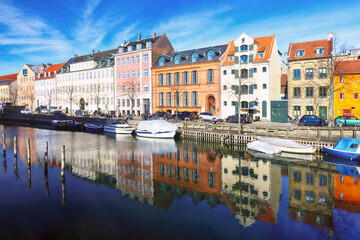 Fototapeta premium Copenhagen christianshavn canal with boats in old town. Famous tourist spot in Denmark with colorful historical buildings. Nyhavn Harbor