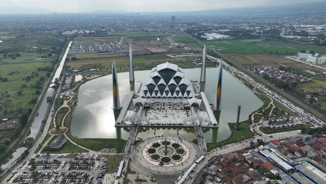 Aerial view of the modern Masjid Raya Al Jabbar with its unique geometric architecture and tall minarets surrounded by water in Kecamatan Gedebage, Jawa Barat, Indonesia.