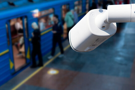 Security camera observes people at subway station while train arrives in the evening