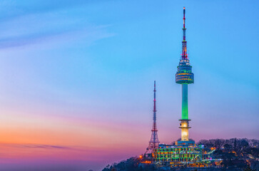 Obraz premium Beautiful twilight night view of the illuminated N Seoul Tower glowing green on Namsan mountain under a vibrant pastel sunset sky, Seoul, South Korea.