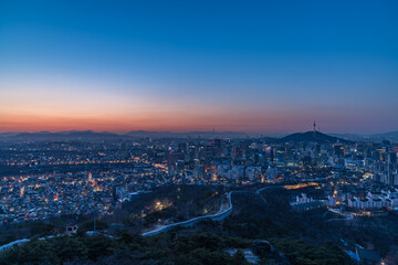 Fototapeta premium Stunning twilight sunset over Seoul city with the illuminated ancient Seoul City Wall on Inwangsan mountain and N Seoul Tower on Namsan in the background, South Korea.