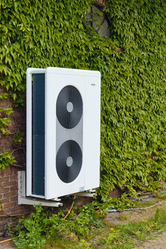 Sustainable energy heat pump system on brick wall with green ivy in Den Oever netherlands for eco-friendly home heating residential installation