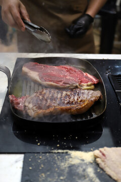 chuletones de carne roja de ternera fri&eacute;ndose en una sart&eacute;n a la plancha