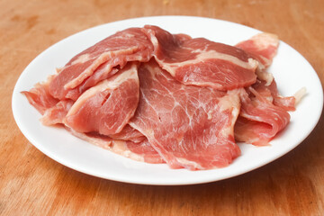 Fototapeta premium flat lay of raw beef pieces in a plate on wooden table