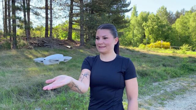 A young woman in athletic wear lets a selfie drone land on her hand