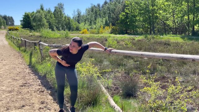 A woman jogging on a dirt road is experiencing pain and a stitch