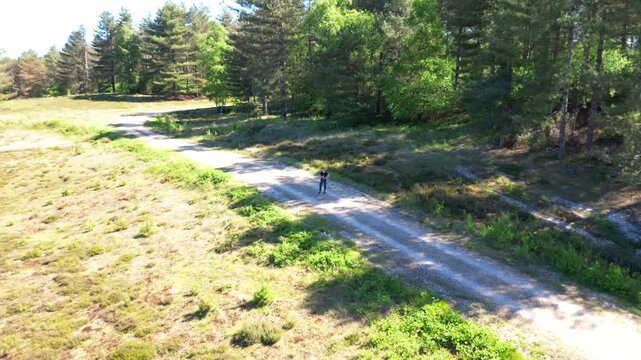Drone shot of a young woman after a run, drinking water from a bottle