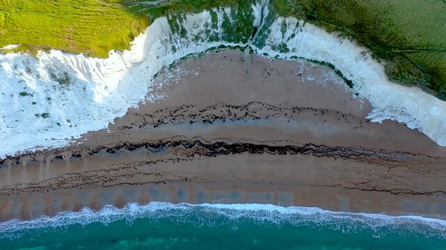 An aerial view of the Jurassic Coast white cliffs and layered rock formations meeting the sea in southern England