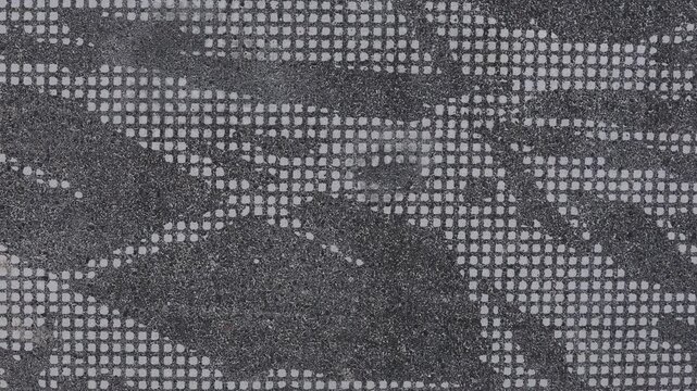 4K video of a gray wall texture featuring a small repeating decorative pattern. The close-up view highlights fine details, surface structure, and subtle geometric design. 