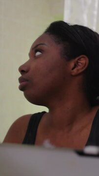 Young African American Woman confronting feelings of uncertainty while looking down at mirror reflection creating emotionally charged moment of self evaluation