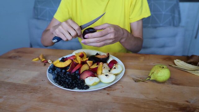 Person cutting fresh nectarine near blueberries pears and plums on kitchen Full HD table video