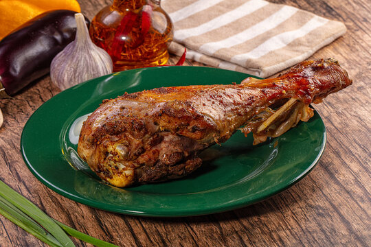 Roasted turkey leg with spices and fresh vegetables on green plate