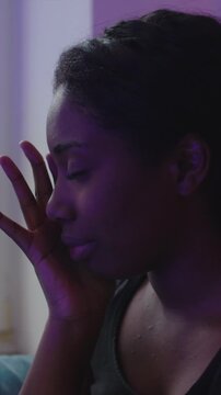 Young African American Woman experiencing emotional distress while seated on sofa expressing anxiety fear uncertainty and the burden of unresolved personal challenges