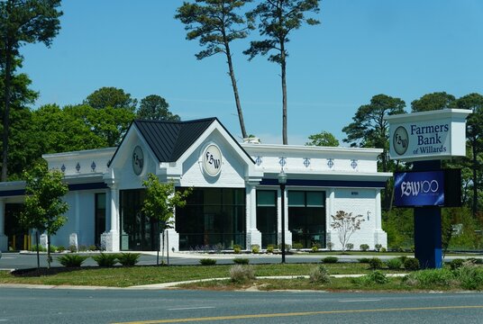 Ocean City, Maryland, U.S.A - May 22, 2026 - Farmers Bank of Willards building with white brick exterior, blue signage, landscaped grounds, and centennial service message.