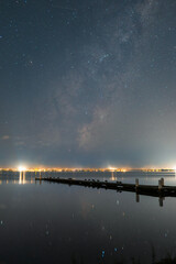 Obraz premium View of milky way rising above the jetty by the lake.