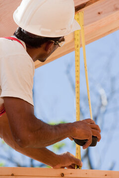 Carpenter measuring a wooden beam
