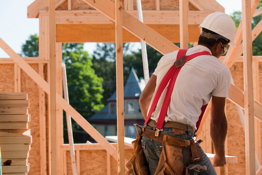 Carpenter carrying a wooden rafter
