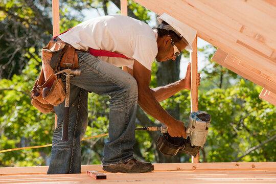 Carpenter working with a nail gun on stud