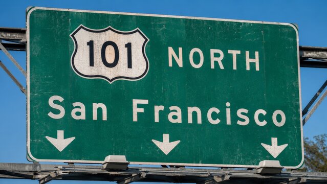 A green overhead highway sign points the way North on US Route 101 towards San Francisco, set against a clear blue sky