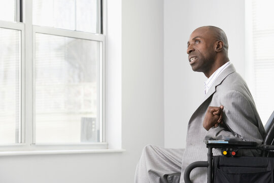 Businessman with Cerebral Palsy looking out through the office window