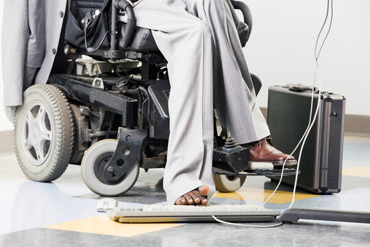 Businessman with Cerebral Palsy working on a computer with his foot