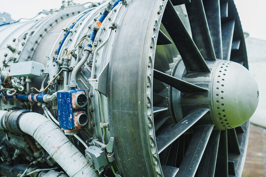 Close view of a large aircraft jet engine with complex components, taken at an airport during daylight
