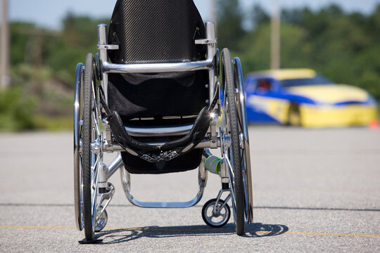 Wheelchair and race car in background