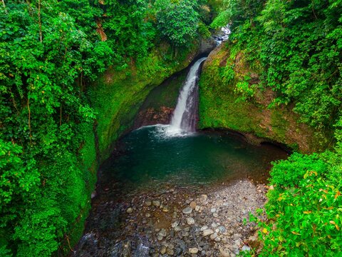 Aerial view of Palak Siring Kemumu waterfall cascading into a pool surrounded by lush tropical rainforest Kecamatan Arma Jaya, Bengkulu, Indonesia.